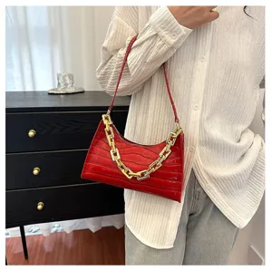 Red crocodile pattern baguette bag detail with luxury gold chain strap and stylish leather texture.