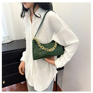 Green crocodile pattern baguette bag detail showing the chic chunky gold chain and leather texture.