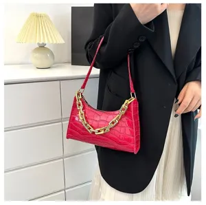 Close-up of trendy crocodile pattern baguette shoulder bag with chunky gold chain detail.