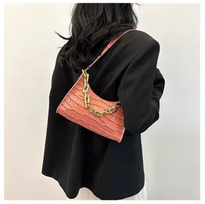 Detail view of pink crocodile texture baguette shoulder bag with gold chain strap.
