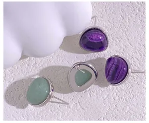 Close-up detail of geometric quartz stud earrings with purple banded and green natural stones.