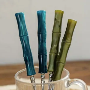 Detailed shot of stainless steel cutlery with stylish bamboo joint resin handles in teal and green.