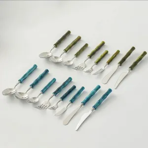 Stainless steel flatware set with green and blue bamboo handle design for dining table detail.