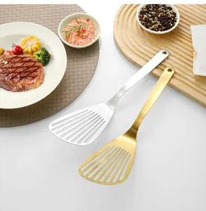 Stainless steel slotted cooking spatula detail view showing gold and silver finishes in kitchen.