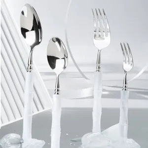 Stainless steel cutlery set detail featuring white bamboo style handle spoons and forks.