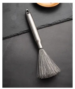 Dettaglio spazzola per pentole in acciaio inossidabile con setole metalliche e foro di aggancio.