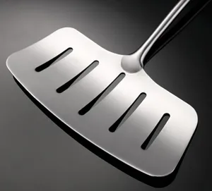 Stainless steel slotted spatula detail close-up, showing metal texture and oil drain slots.