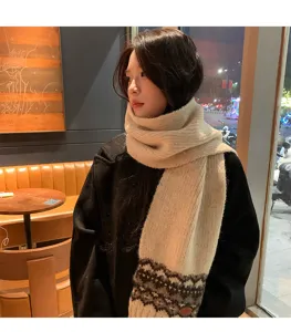 Close-up detail of beige knit scarf with traditional fair isle pattern worn in cozy cafe.