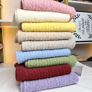 Detailed view of colorful cable knit winter scarves pile, soft wool blend warm fashion texture.