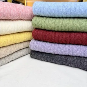 Detailed view of colorful knitted cable scarves stack, showing rich texture and solid colors.