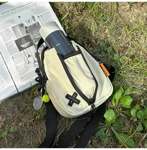 Outdoor cycling crossbody bag detail with grid pattern, front pocket, bottle holder and charm.