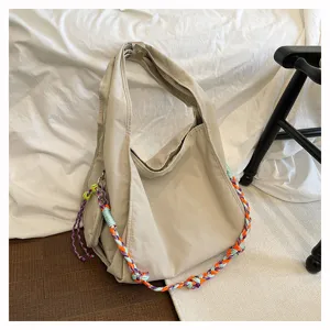 Vista dettagliata della borsa a tracolla in nylon beige con tracolla intrecciata colorata.
