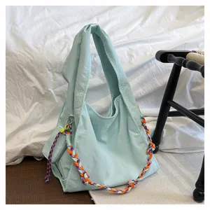 Vista dettagliata della borsa a tracolla in nylon azzurro con spallacci intrecciati colorati.