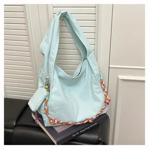 Vista dettagliata della borsa in nylon azzurro con tracolla intrecciata e una piccola pochette.