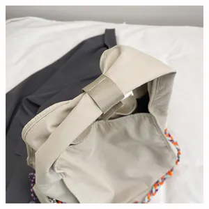 Dettaglio borsa a tracolla pendolare in nylon con cinturino e bordo intrecciato colorato.