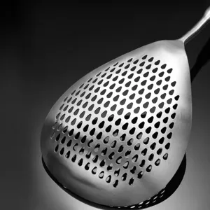 Stainless steel skimmer spoon with evenly distributed draining holes for home kitchen use.