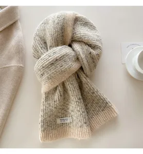 Detail view of a cozy wool-blend speckled knit scarf in beige with a stylish brand tag.
