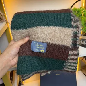 Close-up detail of cozy winter striped knit scarf, showing soft wool texture and brand label.