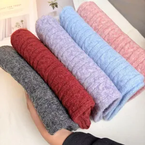 Detail view of soft wool blend cable knit scarves in assorted cozy winter colors.