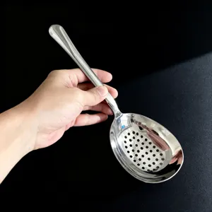 Détail de cuillère de service ajourée en acier inoxydable avec bol perforé.