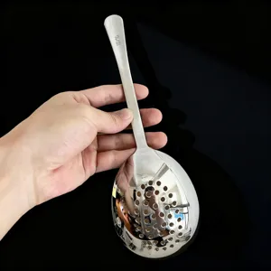 Détail de la cuillère écumoire en acier inoxydable avec marquage sur manche et cuve perforée.