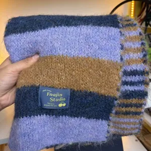 Closeup detail of women's cozy striped wool blend winter scarf warm neckwear item.