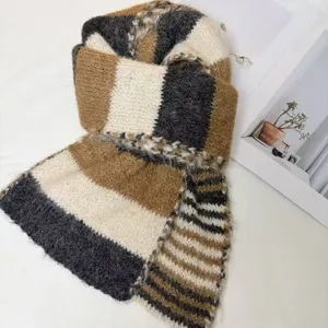 Detailed view of a cozy color-block knit winter scarf featuring warm brown, black and white tones.