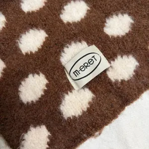 Close-up shot of the soft wool knit scarf fabric, showing detailed polka dot texture and label.