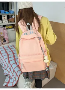 Vista dettagliata dello zaino casual rosa con lettere ricamate e grazioso ciondolo.
