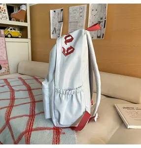 Vista dettagliata di uno zaino casual minimalista con spallacci rossi e ricamo laterale.