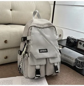 Detail view of the light grey utility backpack featuring checkered front pockets and multi compartments.