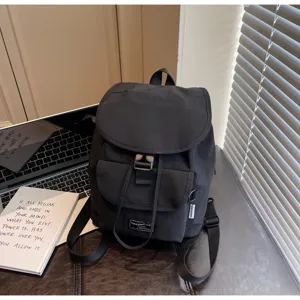 Minimalist black drawstring backpack detail, showing fabric texture, front pocket and strap.