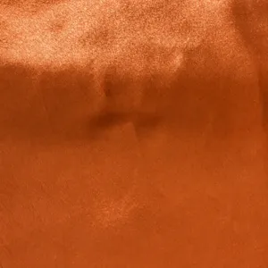 Orange shiny fabric detail closeup texture for Halloween cloak costume garment making.