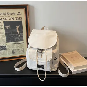 White canvas backpack detail view, minimalist drawstring closure, casual daily wear style.