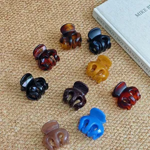 Close-up detail shot of multiple colorful plastic hair claw clips arranged on textured mat.