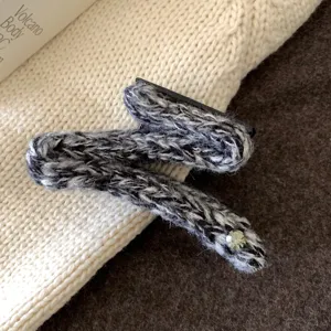 Détail de pince à cheveux tricotée noire et blanche, accessoire en laine texturée.