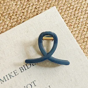 Detailed close-up of dark blue hair claw clip with golden metal spring for elegant hairstyles.
