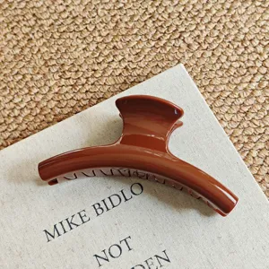 Detailed view of glossy brown hair claw clip on fabric, perfect for thick hair styling.