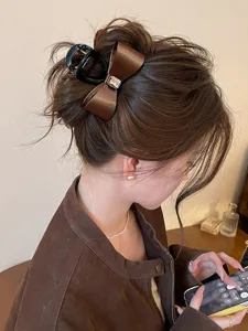 Detail shot of a brown satin bow hair claw clip with a sparkling rhinestone in the center.