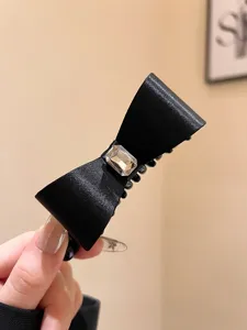 Black satin bow hair claw clip with crystal rhinestones for elegant styling and secure hold.