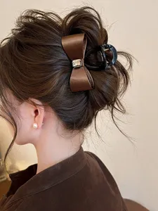 Brown satin bow hair claw clip with sparkly rhinestone for elegant half-up hairstyles and buns.