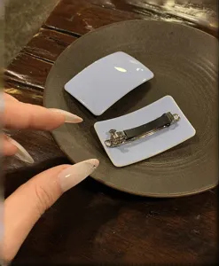 Dettaglio del fermaglio per capelli in acetato azzurro con superficie liscia e molla.
