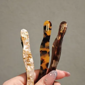 Close-up of stylish acetate hair clips with wave design and tortoise shell patterns.