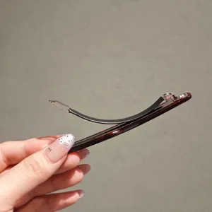 Close-up detail view of elegant tortoiseshell acetate hair clip with wave spring clasp.