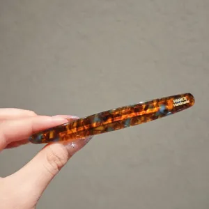 Detail view of the elegant tortoiseshell acetate hair clip with golden handmade lettering.