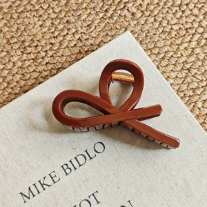 Detailed view of large brown resin hair claw clip with unique abstract loop design and spring.