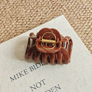 Large brown resin hair claw clip detail with metal spring for thick hair styling and daily wear.