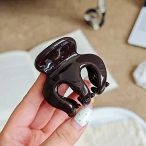 Close-up of a dark brown hair claw clip, glossy finish, secure hold for buns and ponytails.