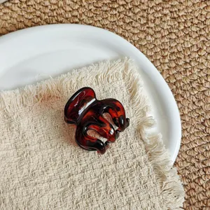 Detailed close-up of a stylish brown tortoiseshell hair claw clip resting on a fabric napkin.
