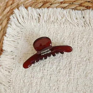 Close-up detail of a dark brown acetate hair claw clip featuring elegant handmade lettering.